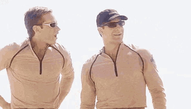 two men in military uniforms are standing next to each other and talking .