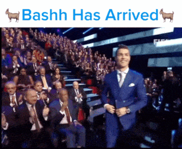 a man in a suit stands in front of a crowd with the words bashh has arrived
