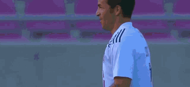 a man wearing a white adidas jersey stands in front of a sign that says pilser