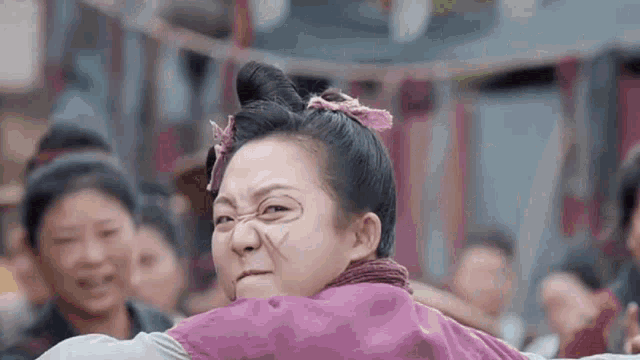 a woman in a purple dress is making a funny face in front of a crowd .