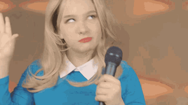 a woman in a blue sweater is holding a microphone