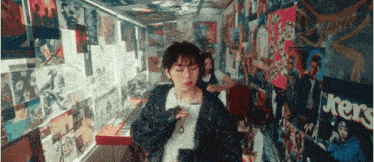 a woman is singing into a microphone in a room with posters on the wall including one that says j.kers