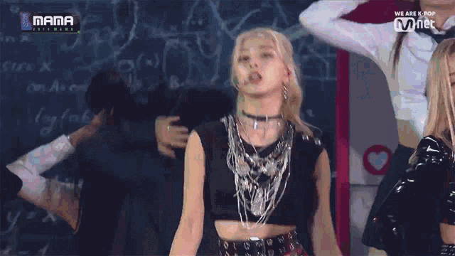 a woman in a black crop top is dancing in front of a chalkboard that says mama