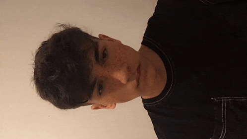 a young man with freckles on his face is wearing a black t-shirt