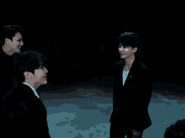 a group of men in suits and ties are standing together in a dark room