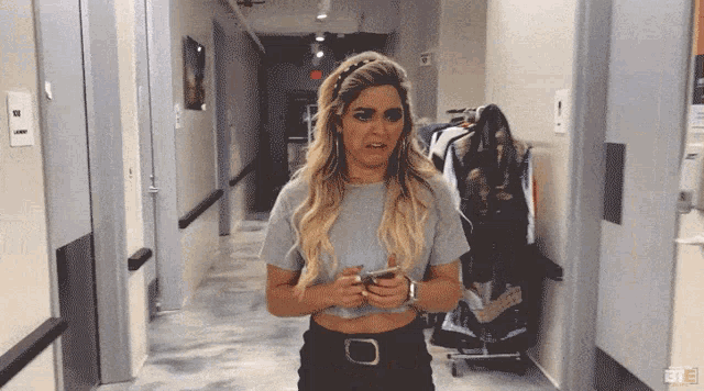a woman standing in a hallway with a phone in her hand and a sign that says exit