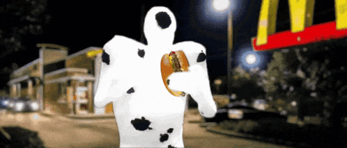 a dalmatian holding a hamburger in front of a mcdonald 's