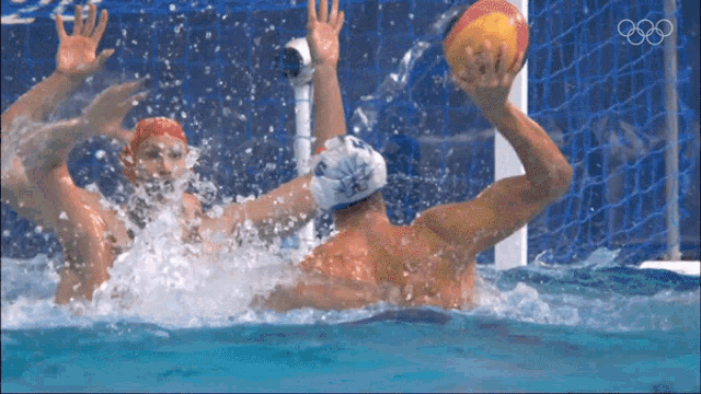 a water polo game is being played with the olympics logo in the background