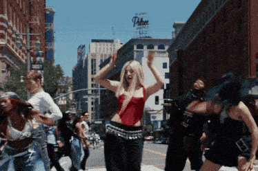 a woman in a red top is dancing in front of a building that has the word palace on it