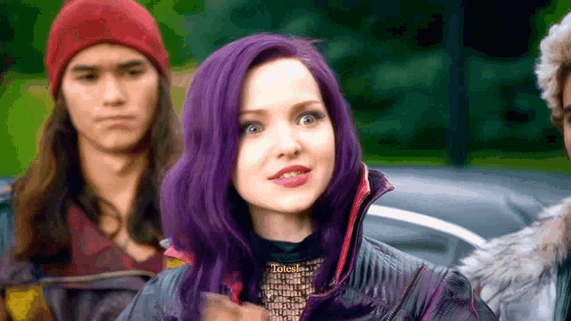 a woman with purple hair is sitting in a car next to a man in a red hat .