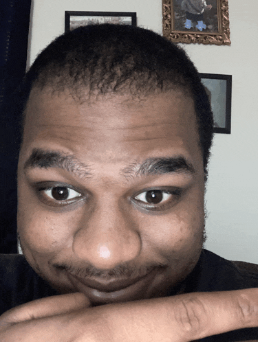 a close up of a man 's face with a picture of a man on the wall behind him