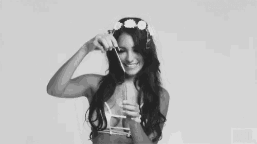 a woman with a flower crown on her head is blowing soap bubbles .