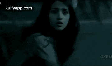 a woman with a surprised look on her face is standing in the dark .
