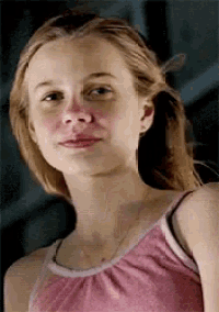 a young woman in a pink tank top is looking at the camera .