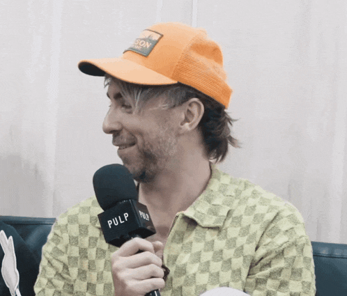 a man in an orange hat is holding a microphone that says pulp