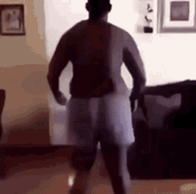 a man in shorts is dancing in a living room .