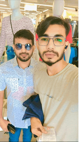 a man wearing sunglasses stands next to another man wearing a shirt that says ' tommy hilfiger '