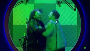 two men are standing next to each other in front of a microphone in a recording studio .