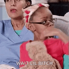 a little girl wearing glasses and a headband is sitting next to a woman and holding a teddy bear .