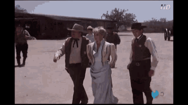 a man in a cowboy hat is walking with a woman in a dress