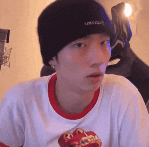a man wearing a white shirt and a black beanie has the word like on his hat