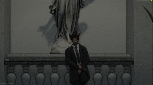 a man in a suit and tie sits on a railing in front of a statue