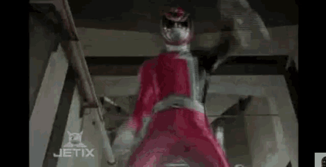 a red power ranger is standing next to a black power ranger in a building .