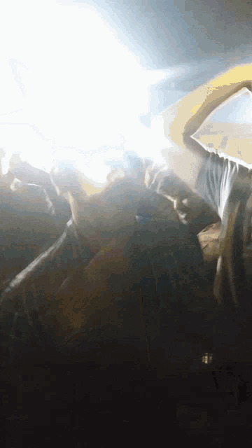 a group of people are dancing in a dark room with a light shining through the ceiling