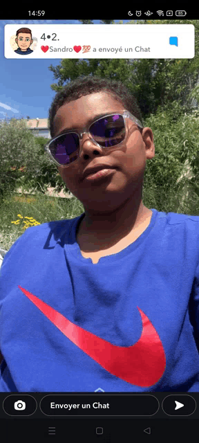 a boy wearing sunglasses and a blue nike shirt is on a cell phone screen