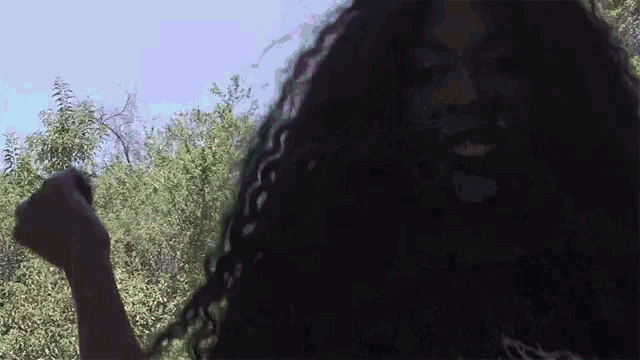 a woman with long curly hair is smiling in the dark