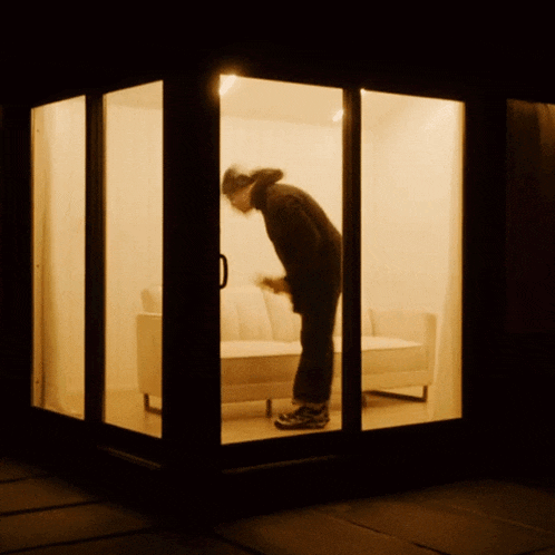 a man standing in front of a couch in a room with a sliding glass door