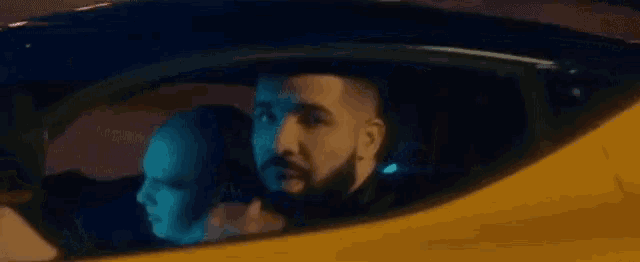 a man with a beard is sitting in a yellow car .