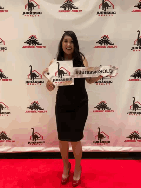 a woman holds up a sign that says #jurassic sold