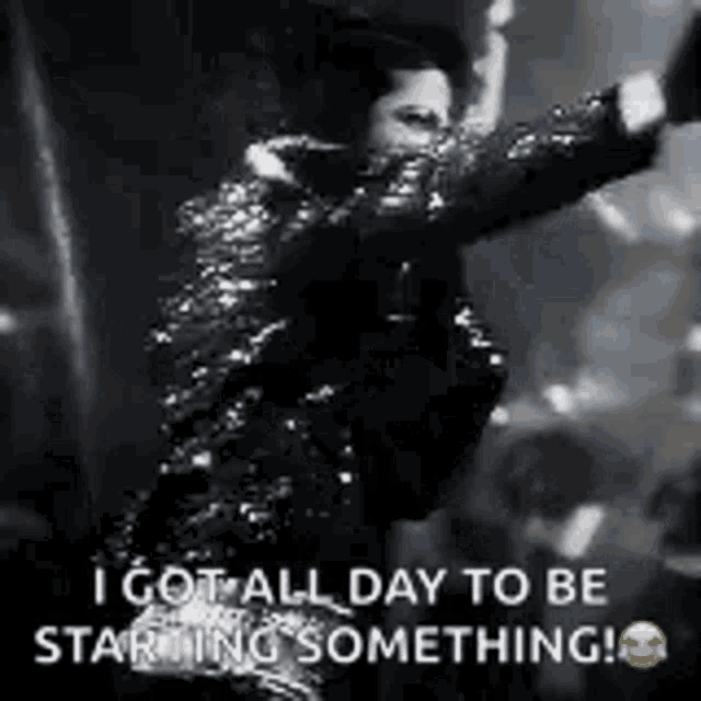 a black and white photo of a man in a sequined jacket standing on a stage .