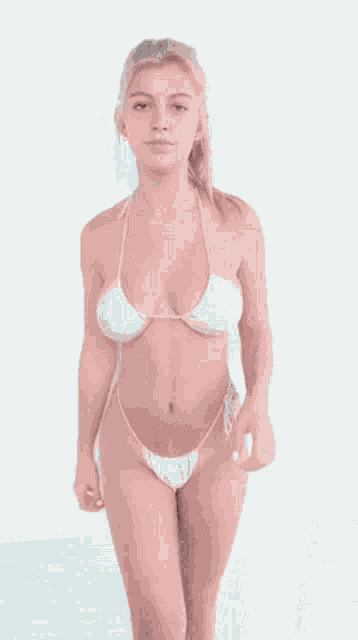 a woman in a white bikini is standing in front of a wall