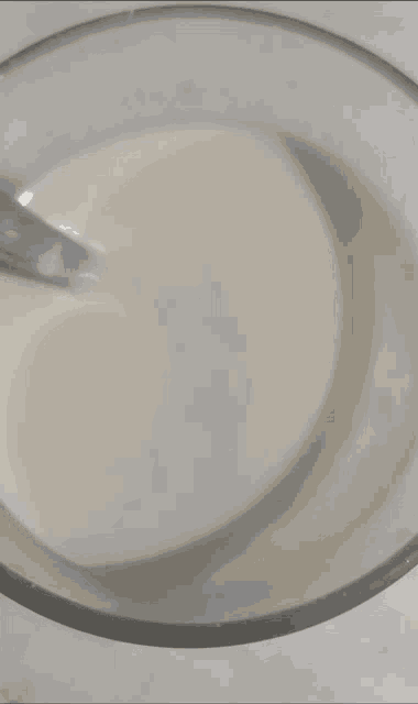 a glass bowl filled with a white liquid with a spoon sticking out of it