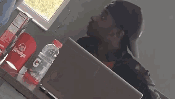 a man is sitting at a table with a laptop and a bottle of gatorade on it