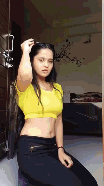a woman in a yellow crop top is sitting on the floor