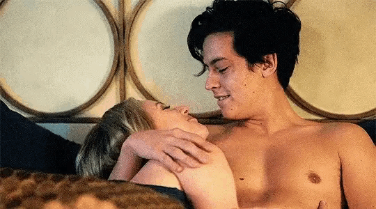a shirtless man and a shirtless woman are laying in bed .