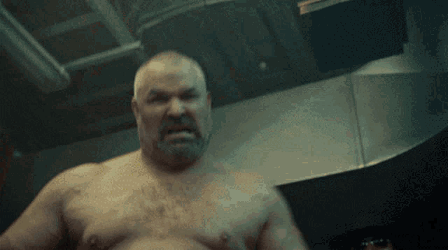 a shirtless man with a beard looks angry