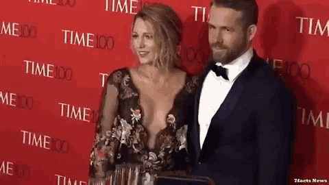 a man and a woman are standing on a red carpet in front of a wall that says time 100 .