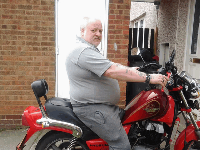 a man sitting on a red motorcycle with the word hyosung on the side