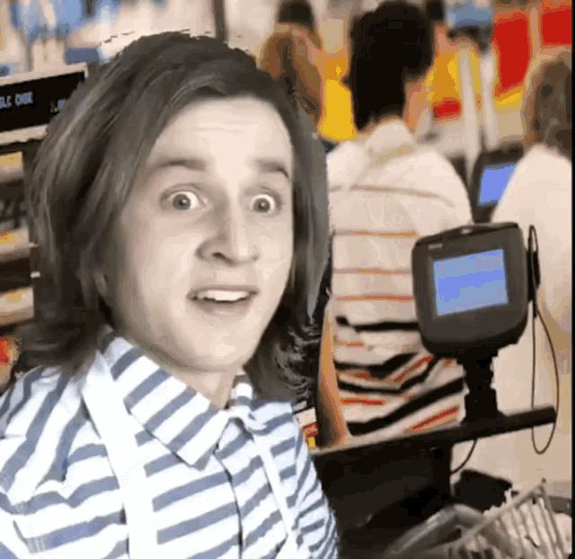 a man in a striped shirt is standing in front of a sony display