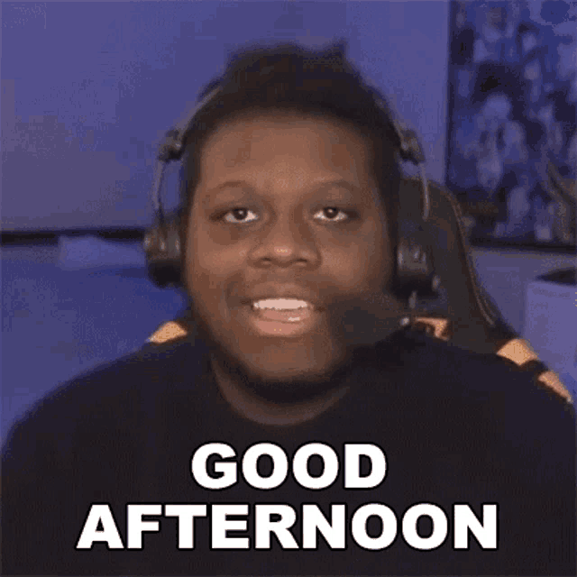 a man wearing headphones and a microphone is saying `` good afternoon '' while sitting in a chair .