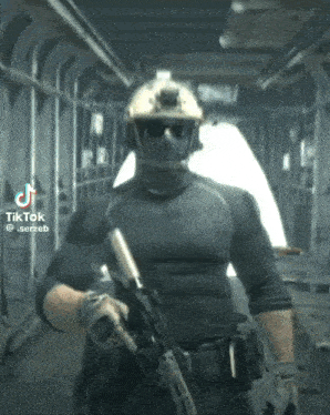 a man in a military uniform is holding a gun and wearing sunglasses and a helmet