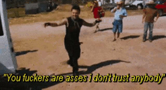 a group of people are walking down a dirt road with the caption " you fuckers are asses i don t trust anybody