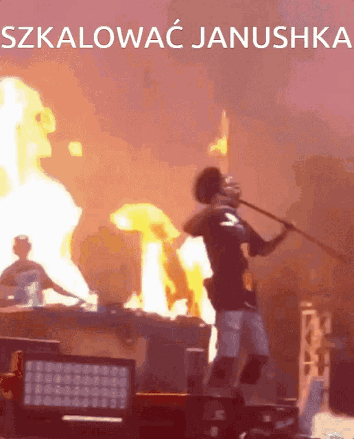 a man is holding a stick in front of a fire and the words szkalowac janushka