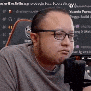 a man with glasses is sitting in front of a microphone