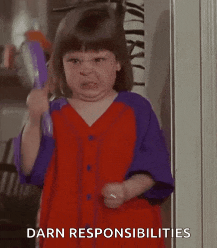 a little girl in a red and purple dress is holding a brush and making a face .