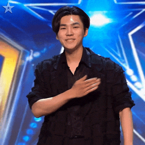 a man stands on a stage with his hand on his chest and a star in the background